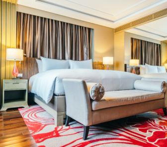 Contemporary bedroom interior design in Kolkata, featuring a large bed and a bold red rug.